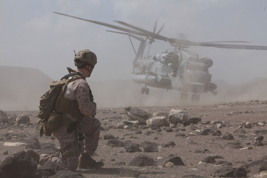Photo of Recon Marine providing security as a CH-53E helicopter takes off